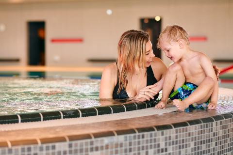 Mutter mit Kind am Beckenrand im Warmwasserbecken im Schwaketenbad